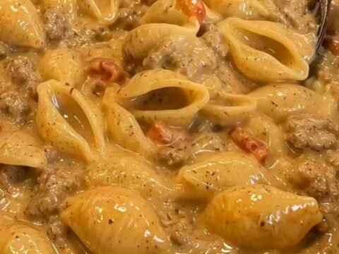 A steaming bowl of creamy taco pasta with large shells and a rich meat sauce.