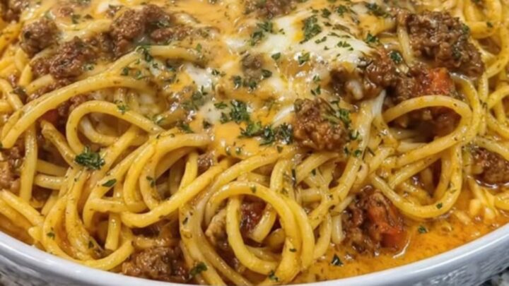 A close-up of a steaming portion of bolognese spaghetti being lifted with tongs, showcasing a long