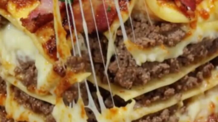 A towering slice of garlic parmesan bacon cheeseburger lasagna showing layers of melted cheese and beef.