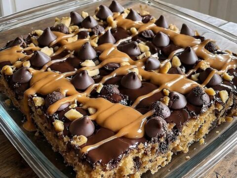 A warm, sliced peanut butter cup dump cake in a clear glass baking dish with visible layers of chocolate and peanut butter.