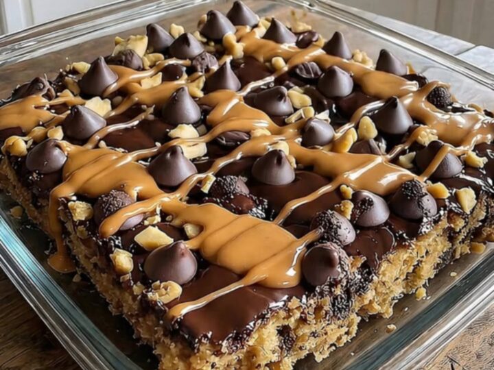 A warm, sliced peanut butter cup dump cake in a clear glass baking dish with visible layers of chocolate and peanut butter.