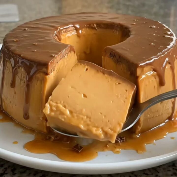 A glossy chocolate pudding ring drizzled with golden caramel sauce on a white plate.