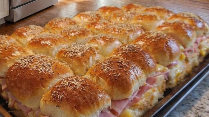 A tray of warm, golden brown ham and cheese sliders fresh from the oven.