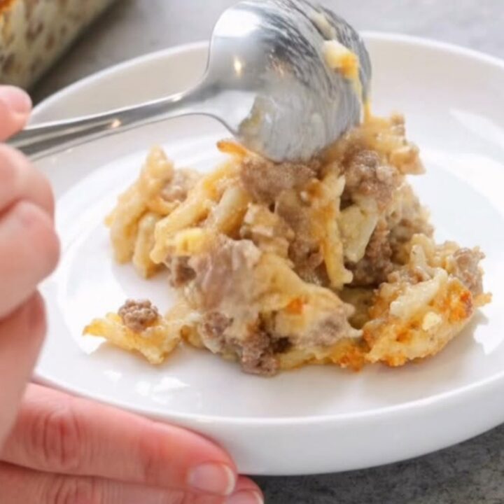 Golden cheesy beef and hashbrown casserole freshly baked in a glass dish with a bubbly crust.