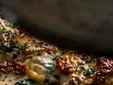 Slow cooker filled with golden chicken thighs nestled in a rich garlic cream sauce with spinach and sun-dried tomatoes