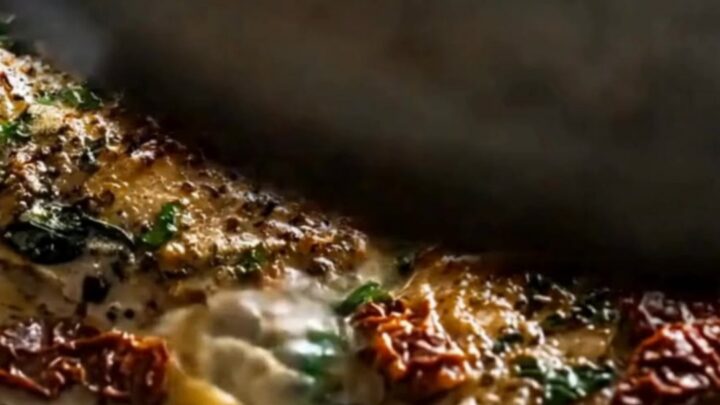 Slow cooker filled with golden chicken thighs nestled in a rich garlic cream sauce with spinach and sun-dried tomatoes