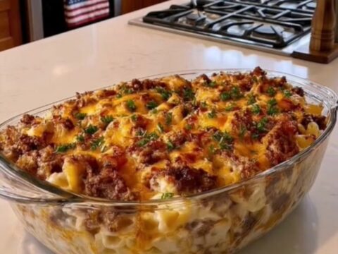 A steaming, bubbly macaroni and beef casserole in a clear glass dish topped with melted cheddar cheese.