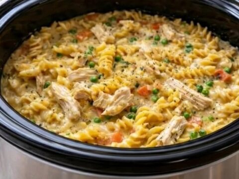 A steaming bowl of creamy chicken pot pie pasta with visible chunks of chicken and vegetables.