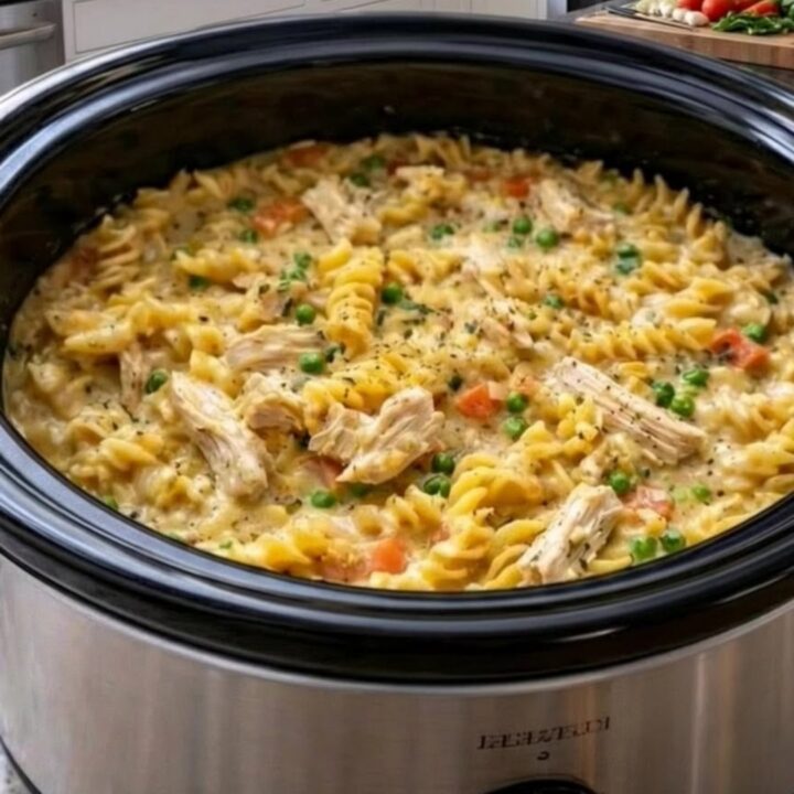 A steaming bowl of creamy chicken pot pie pasta with visible chunks of chicken and vegetables.