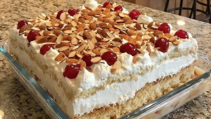 A slice of Heaven on Earth cake in a glass dish showing distinct layers of cake, cherries, and cream.