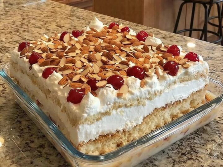 A slice of Heaven on Earth cake in a glass dish showing distinct layers of cake, cherries, and cream.