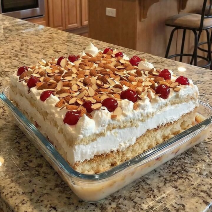 A slice of Heaven on Earth cake in a glass dish showing distinct layers of cake, cherries, and cream.
