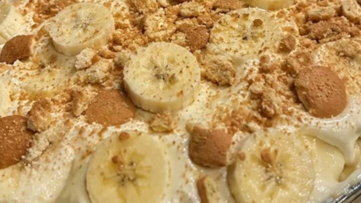 A glass casserole dish filled with layers of creamy banana pudding, sliced bananas, and vanilla wafers.