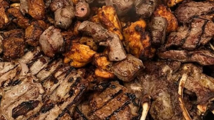 A large metal platter filled with perfectly charred lamb chops and savory meat kebabs.