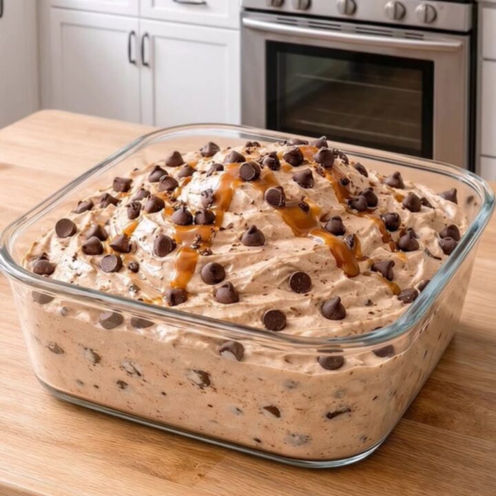 Square glass dish holding creamy peanut butter fluff loaded with chocolate chips and caramel drizzle.