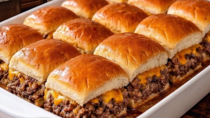 A close-up of golden-brown cheeseburger sliders in a white baking dish with melted cheese.
