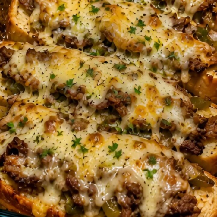 A close-up of a slice of Philly cheesesteak garlic bread bake being lifted with a spatula, showing melted cheese.