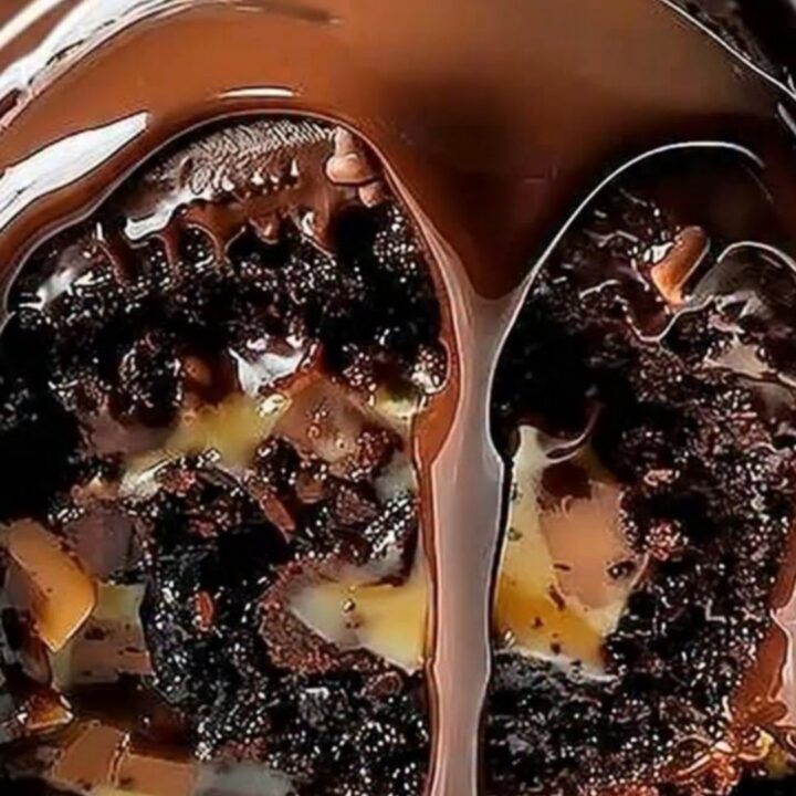 A glossy chocolate-glazed cake roll topped with pecans sitting on a white serving platter.