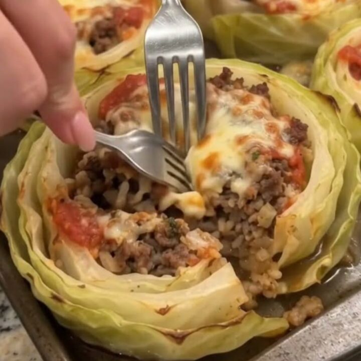 A close-up shot of a baked cabbage ring stuffed with seasoned ground beef, topped with melted