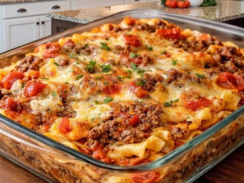 A glass baking dish filled with a cheesy, golden-brown beef Lombardi casserole.
