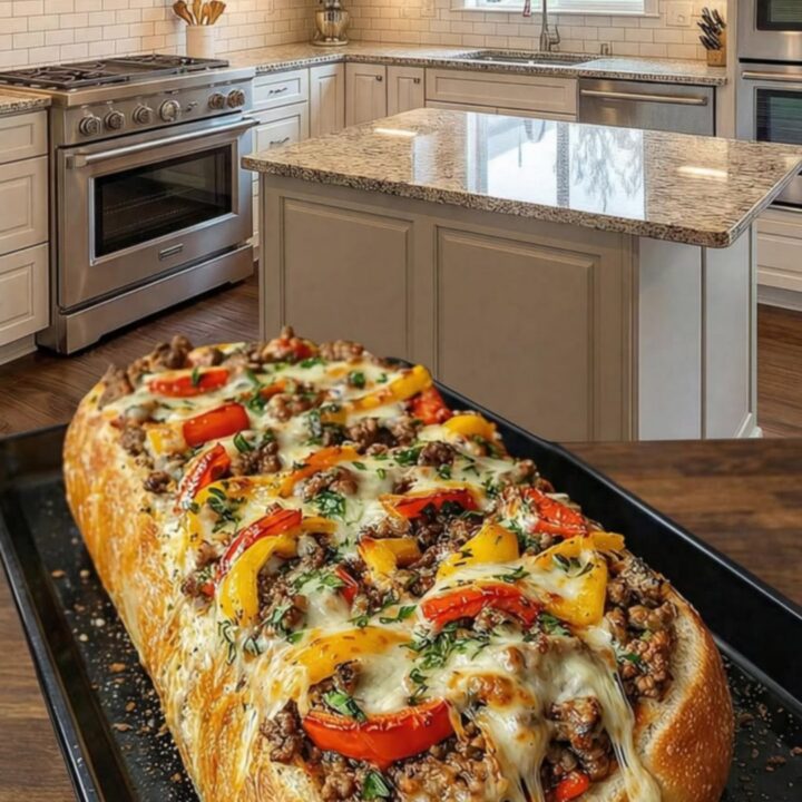 A golden, toasted loaf of French bread stuffed with savory ground beef, colorful bell peppers, and melted