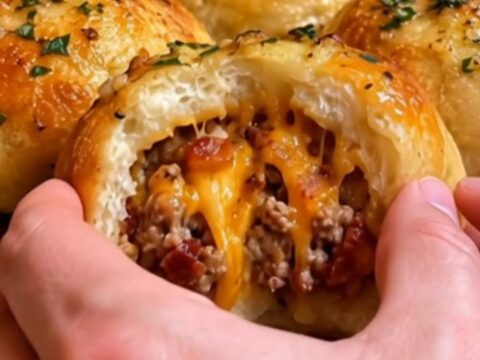 A golden, baked garlic parmesan cheeseburger bomb sitting on a white plate.