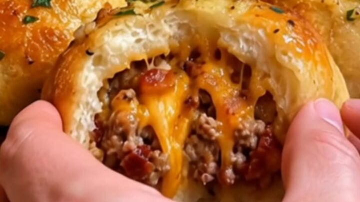 A golden, baked garlic parmesan cheeseburger bomb sitting on a white plate.