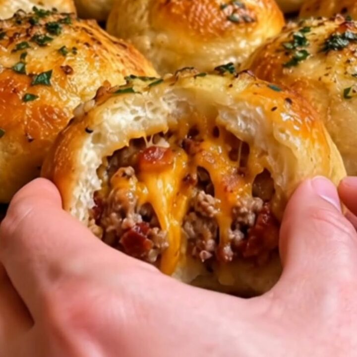 A golden, baked garlic parmesan cheeseburger bomb sitting on a white plate.