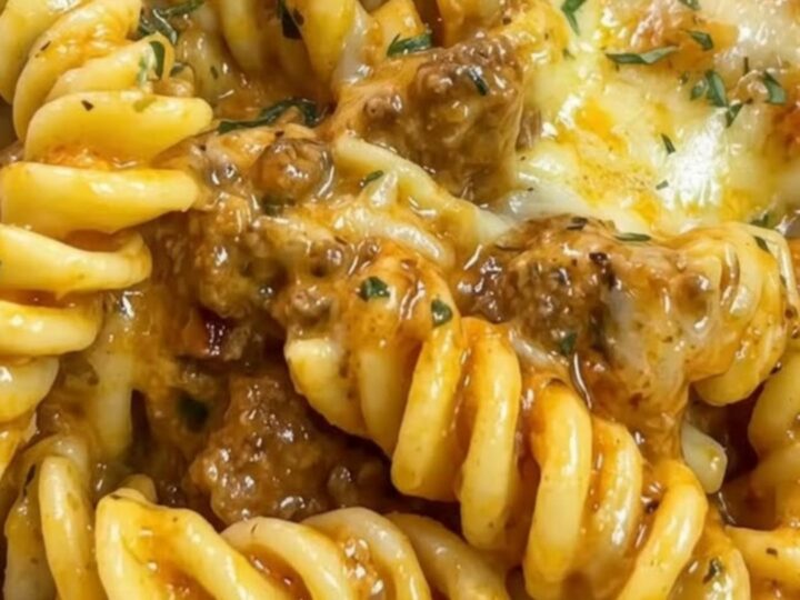 A warm bowl of creamy beef rotini pasta garnished with fresh parsley and showing a thick melted cheese pull