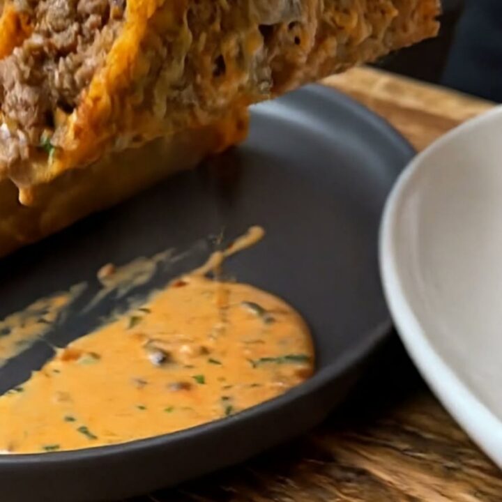 A golden, crispy cheese-shell taco filled with seasoned ground beef and topped with creamy orange sauce.