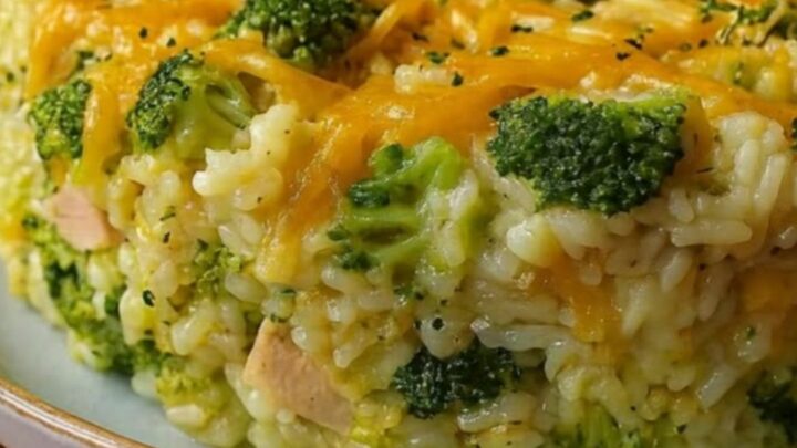 A golden, bubbling chicken and broccoli casserole in a white ceramic dish with melted cheese pulls.