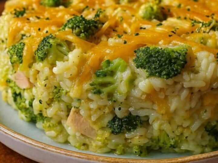 A golden, bubbling chicken and broccoli casserole in a white ceramic dish with melted cheese pulls.