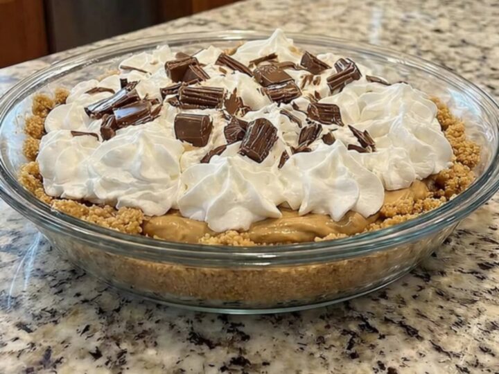 A slice of creamy no-bake peanut butter pie with a graham cracker crust on a white plate.