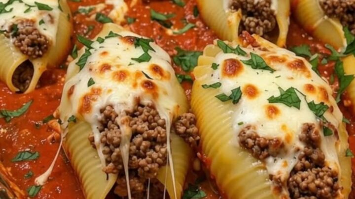 A close-up of a serving of baked beef and cheese stuffed shells on a white plate.