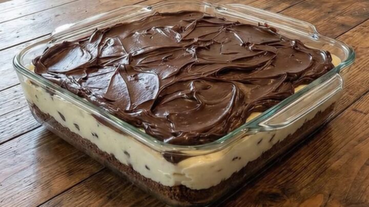 A slice of layered chocolate cream cheese dessert on a white plate with a fork.