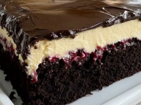 A slice of Black Forest sheet cake on a white plate showing layers of sponge, cherries, and cream.