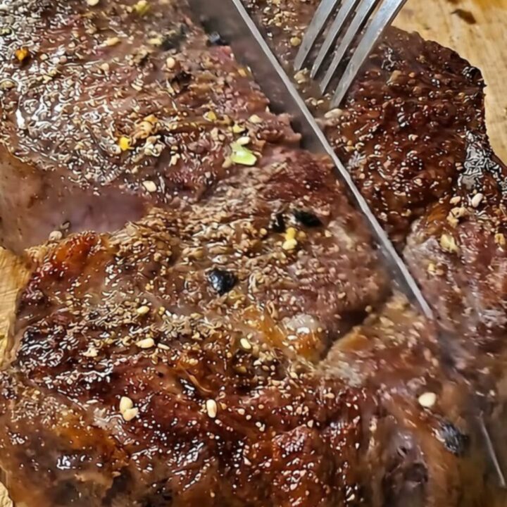 A perfectly seared tomahawk steak with a beautiful brown crust resting on a wooden board.