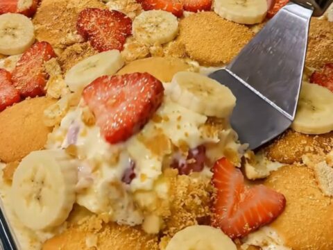 A glass dish filled with layers of creamy vanilla pudding, sliced bananas, fresh strawberries, and vanilla wafers.