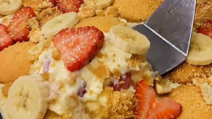 A glass dish filled with layers of creamy vanilla pudding, sliced bananas, fresh strawberries, and vanilla wafers.