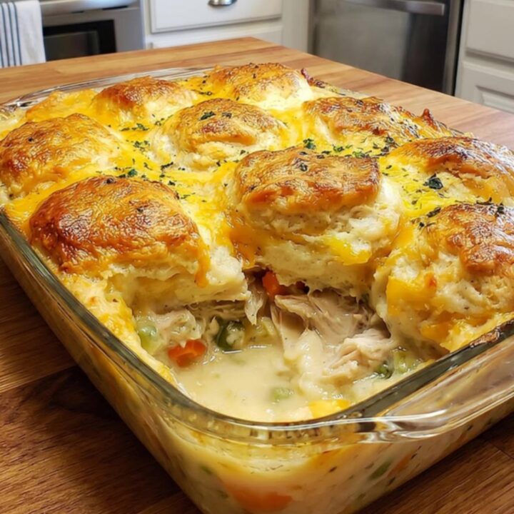 A golden, bubbly chicken cobbler casserole fresh from the oven in a glass dish.