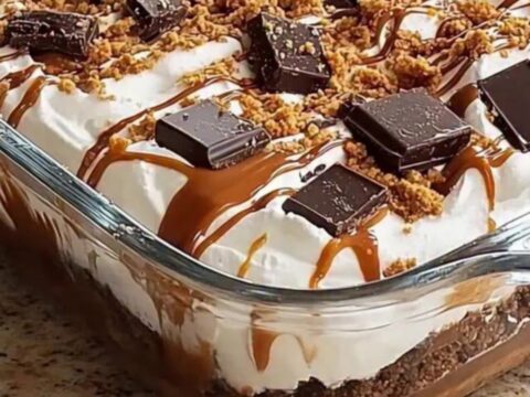 A close-up view of a layered chocolate and caramel dessert in a glass dish, showing distinct, smooth layers.