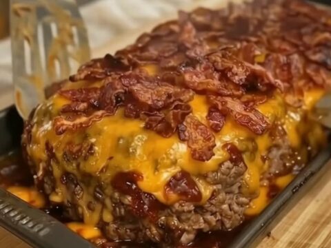 A thick, juicy slice of loaded bacon cheeseburger meatloaf topped with melted cheddar cheese and crispy bacon.
