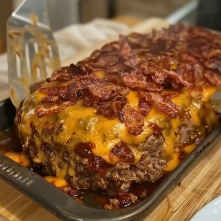 A thick, juicy slice of loaded bacon cheeseburger meatloaf topped with melted cheddar cheese and crispy bacon.