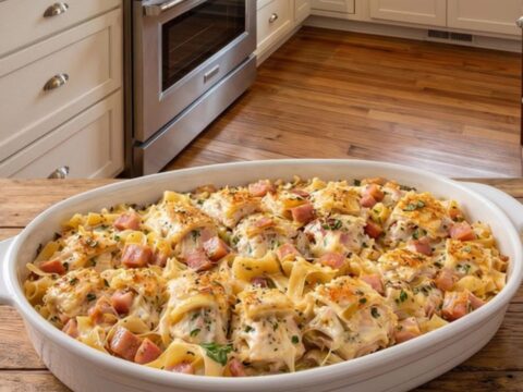 A steaming, golden-baked Chicken Cordon Bleu Casserole in a white oval dish.