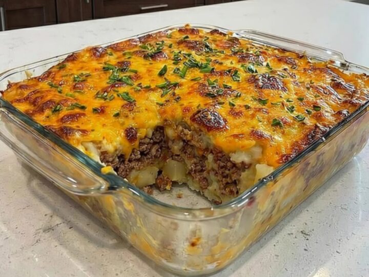 A close-up of a loaded potato meatloaf casserole in a glass dish with a spatula lifting a portion.