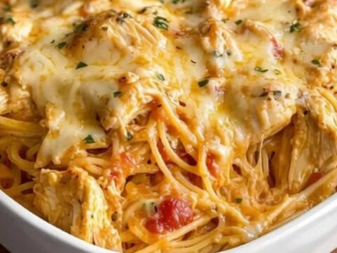 A warm ceramic casserole dish filled with creamy Rotel chicken spaghetti topped with melted golden mozzarella cheese.