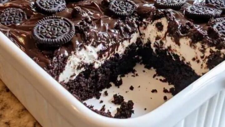 A slice of rich chocolate earthquake cake with a swirl of cream cheese, topped with fudge and crushed Oreo cookies.