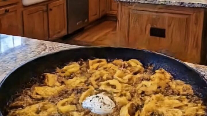 A steaming portion of beef tortellini in a large skillet on a granite countertop.