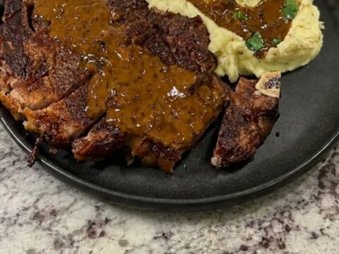 A plate featuring seared, sliced steak with rich gravy and creamy mashed potatoes.