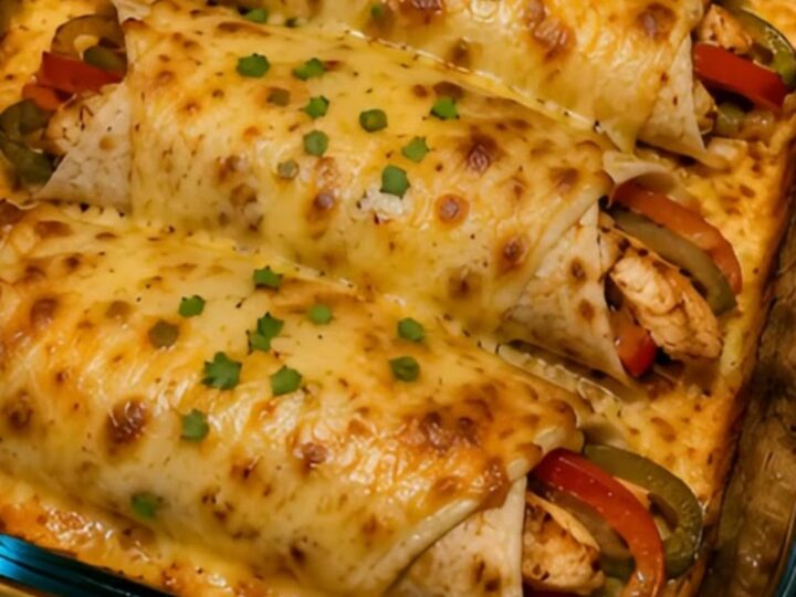 A glass baking dish filled with four golden-brown chicken fajita wraps topped with melted, gooey pepper jack cheese.